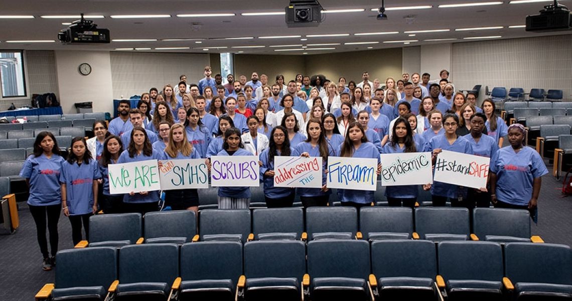Group of students holding signs in a lecture hall